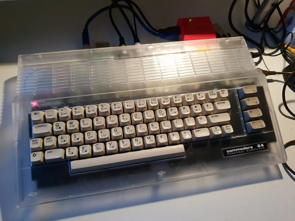 Commodore 64C with transparent acrylic case mod, showing the internal circuit board and components through the clear case